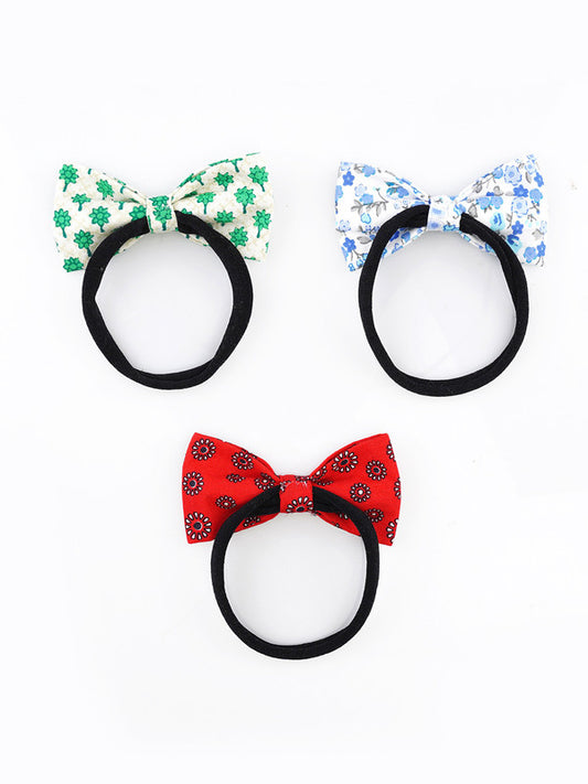 Three floral baby headbands by Choko with black nylon bands and cotton bows in green, red, and blue prints for a stylish and comfortable look.