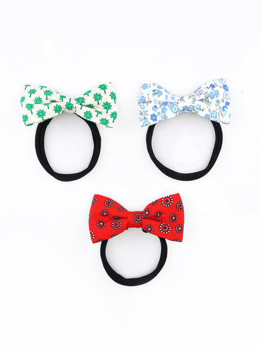 Three floral baby headbands by Choko with black nylon bands and cotton bows in green, red, and blue prints for a stylish and comfortable look.